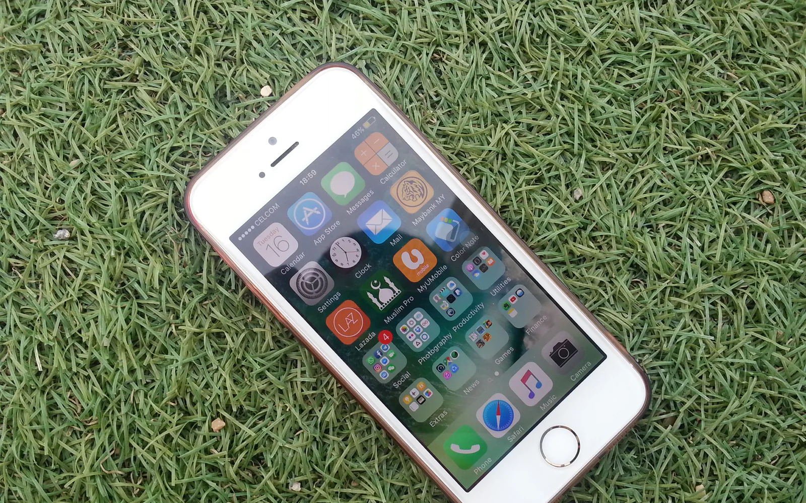 A smartphone displaying app icons lies on green grass.