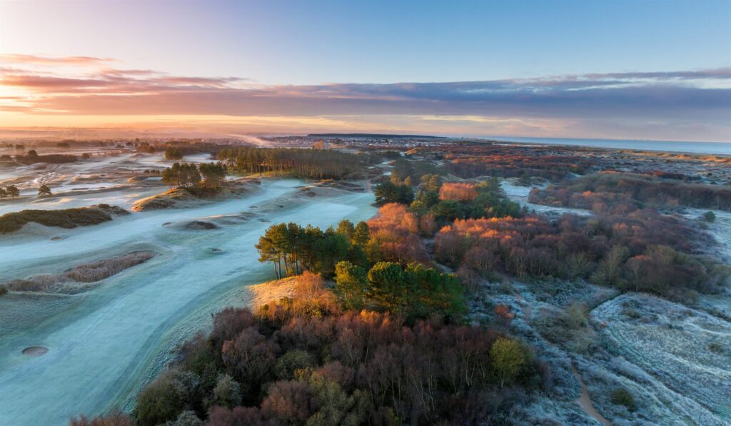 Frost covering a links golf course at sunrise.