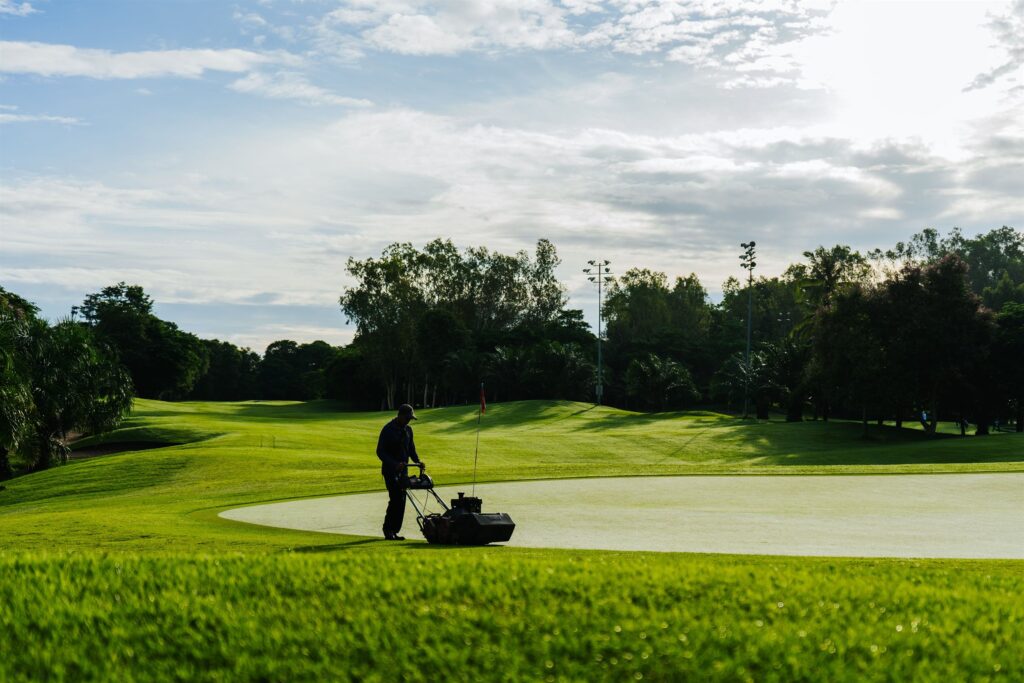 Greenkeeper mowing a golf playing surface